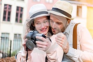 Young attractive couple checking pictures on camera