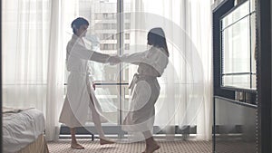 Young attractive couple dancing in bathrobe after arriving to hotel.