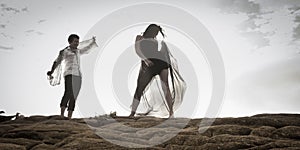 Young attractive couple dancing outdoors on beach rocks