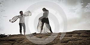 Young attractive couple dancing outdoors on beach rocks