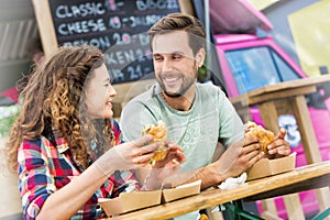 Young attractive couple eating hamburgers against food truck