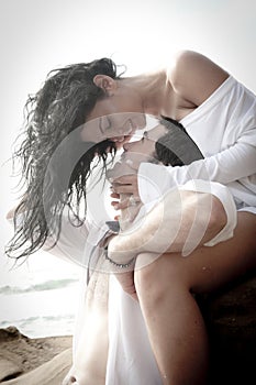 Young attractive couple flirting outdoors on beach rocks