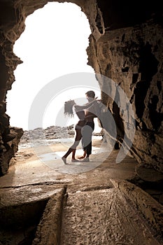 Young attractive couple flirting through rock archway