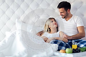 Young attractive couple having breakfast in bed