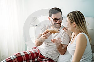 Young attractive couple having breakfast in bed