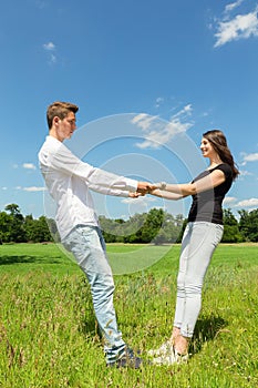 Young attractive couple holding each other in sunny meadow