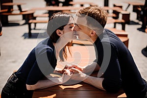 Young and attractive couple holding hands about to kiss over table in restaurant
