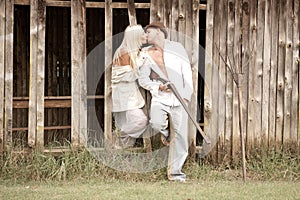 Young attractive couple kissing against wooden barn wall