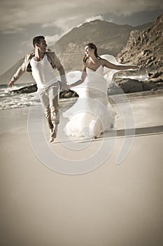 Young attractive couple laughing and running along beach