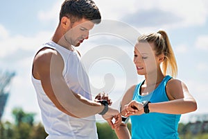 Young attractive couple looking at their watch in park