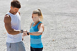 Young attractive couple looking at their watch in park