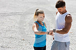 Young attractive couple looking at their watch in park