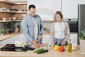 Young attractive couple in love preparing salad from fresh vegetables.
