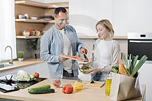 Young attractive couple in love preparing salad from fresh vegetables.