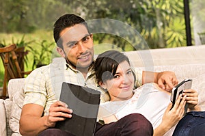Young attractive couple lying in the sofa using