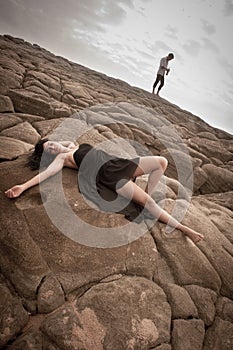 Young attractive couple outdoors on beach rocks