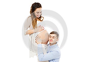 Young attractive couple: pregnant mother and happy father who listening pregnant belly