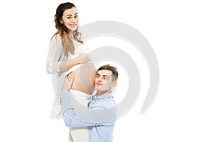 Young attractive couple: pregnant mother and happy father who listening pregnant belly photo