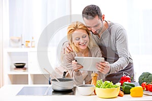 Young attractive couple reading recipe on a tablet