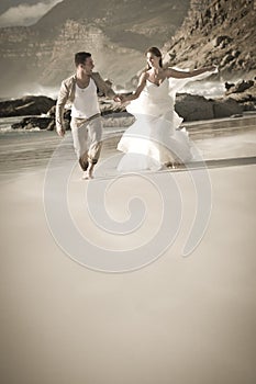 Young attractive couple running along beach wearing white