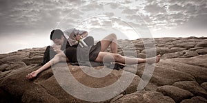 Young attractive couple sharing a moment outdoors on beach rocks