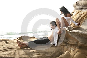 Young attractive couple sharing a moment outdoors on beach rocks