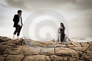 Young attractive couple sharing a moment outdoors on beach rocks