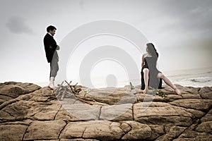 Young attractive couple sharing a moment outdoors on beach rocks