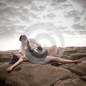 Young attractive couple sharing a moment outdoors on beach rocks