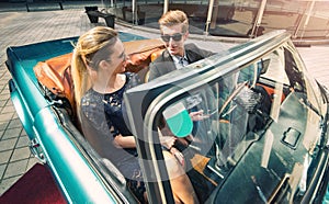 Young and attractive couple sitting in a luxurious retro car