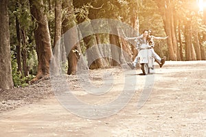 Young attractive couple traveling on scooter along dirt road photo