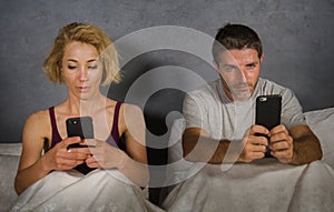 Young attractive couple using mobile phone in bed ignoring and neglecting each other obsessed networking in internet addiction and