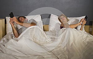 Young attractive couple using mobile phone in bed ignoring and neglecting each other obsessed networking in internet addiction and photo