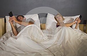 Young attractive couple using mobile phone in bed ignoring and neglecting each other obsessed networking in internet addiction and