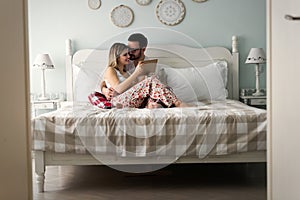 Young attractive couple using tablet in bedroom