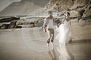 Young attractive couple walking along beach wearing white