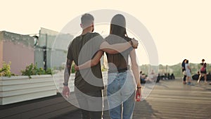 Young attractive couple walking down the street together hand in hand on sunset backround. Slow motion from 100fps