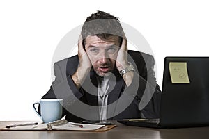 Young attractive depressed and frustrated businessman working at office computer desk desperate and overwhelmed feeling upset