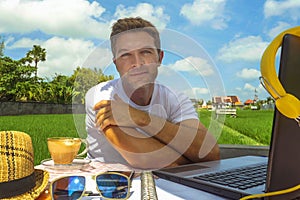Young attractive digital nomad man working on line outdoors with laptop computer and mobile phone as freelancer and independent jo
