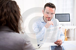 Young attractive employer analysing resume of woman