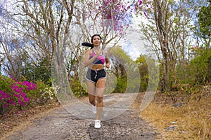 Young attractive and exotic Asian Indonesian runner woman in jogging workout outdoors at countryside road track nature running