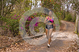 Young attractive and exotic Asian Indonesian runner woman in jogging workout outdoors at countryside road track nature running