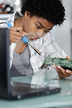 Young attractive female digital electronic engineer repairing pc