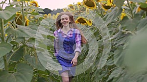 Young, attractive, female farmer running through a sunflower field