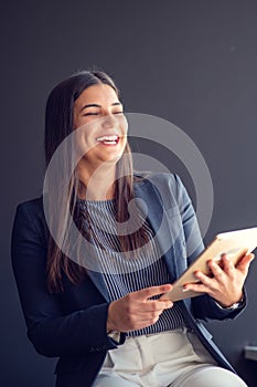 Young attractive female manager working on digital tablet while standing in modern office