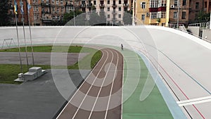 Young attractive female road cyclist is riding at the velodrome. Girl on cycling track. Cycling concept. Drone view