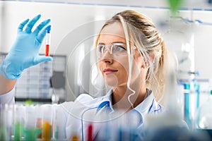 Young attractive female scientist examining test tube with substance probe