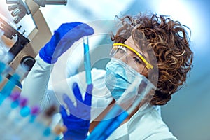 Young attractive female scientist in protective eyeglasses