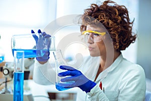 Young attractive female scientist in protective eyeglasses and glove