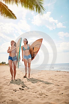 Young attractive female surfers  enjoy a beach